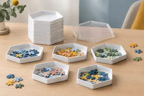 Huit plateaux blancs de tri pour puzzle empilés sous un couvercle transparent, avec des pièces colorées