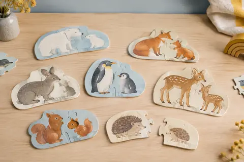Puzzle duo en carton avec des associations d’animaux adultes et de leurs petits, posé sur une table en bois clair.