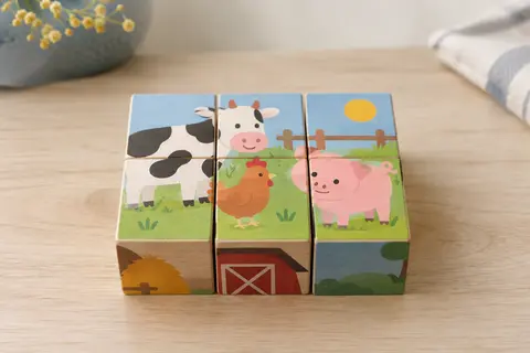 Six cubes en bois assemblés en grille de trois sur deux, formant une image d’animaux de la ferme sur une table claire.
